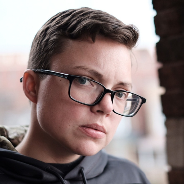 Headshot of young caucasian woman with short dark hair and glasses.